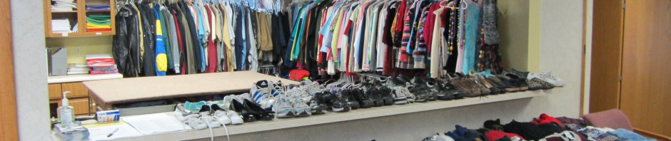 Clothing store with racks and tables displaying apparel and shoes.