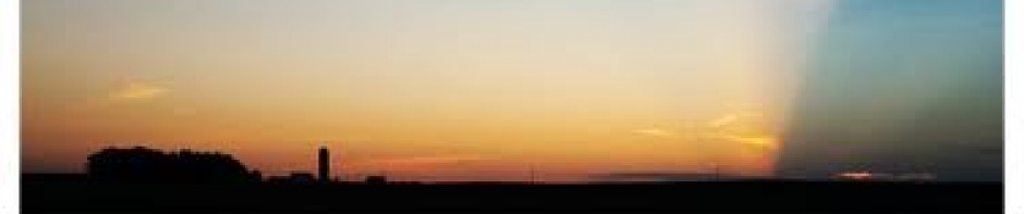 A serene sunset with a gradient sky over a dark horizon.