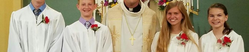 Group of young people and a priest in church attire.