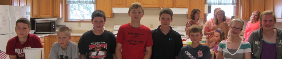 A group of children displaying baked goods in a kitchen.