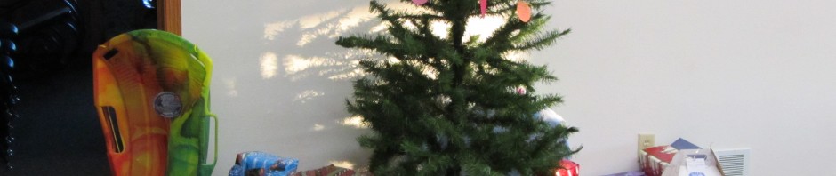 A small Christmas tree surrounded by wrapped gifts in a living room.