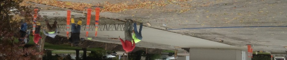 Workers smoothing freshly poured concrete on a residential street.