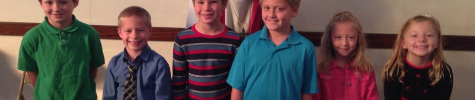 A man smiling with six children in a room with stained glass windows.