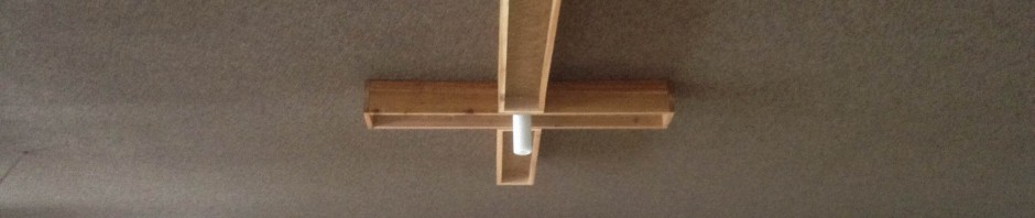 Wooden cross and platform mounted on a ceiling in a room.