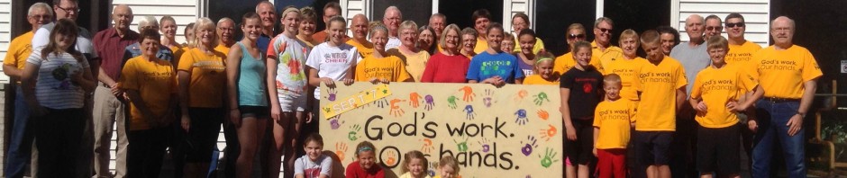 A large group of people holding a colorful banner outside a building.