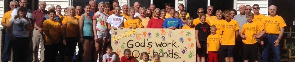 Group holding a banner that reads 'God's work. Our hands.'
