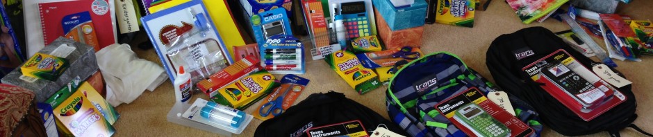 Several backpacks filled with school supplies arranged on the floor.