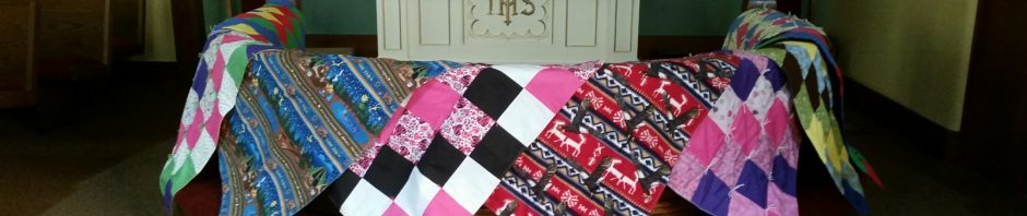 Colorful quilts displayed in front of a church altar.