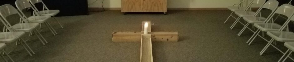A dimly lit room set up for a small ceremony with candles and a wooden balance beam.