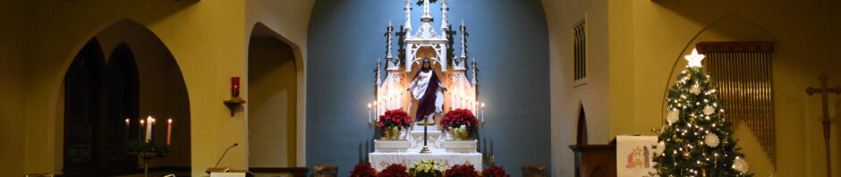 Interior view of a church altar decorated with Christmas lights and a tree.