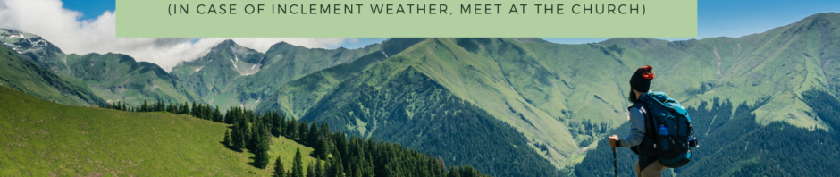 A scenic mountain trail with a hiking path and lush green trees under a clear blue sky.