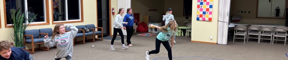 Children practicing fencing in a spacious indoor room.