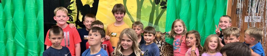 Group of children posing happily in a colorful jungle-themed room.