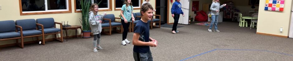 Children playing indoors with jump ropes in a spacious room.