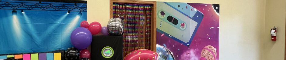 Colorful balloon decorations with speakers and a large number 6 balloon.
