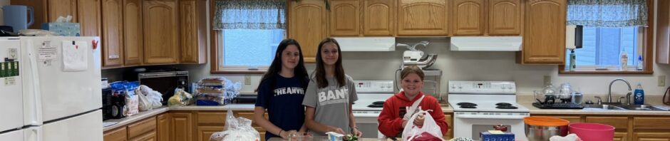 Three people preparing food in a spacious kitchen.