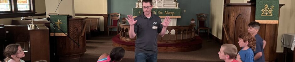 Group of children and an adult in a church setting.