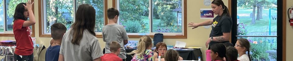 Children and adults engaging in an indoor group activity around a table.
