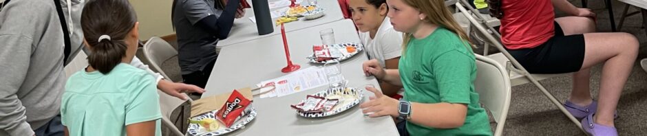 Children and adults engaging in a group activity around a table.