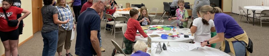 People gathered around tables working on crafts in a community room.